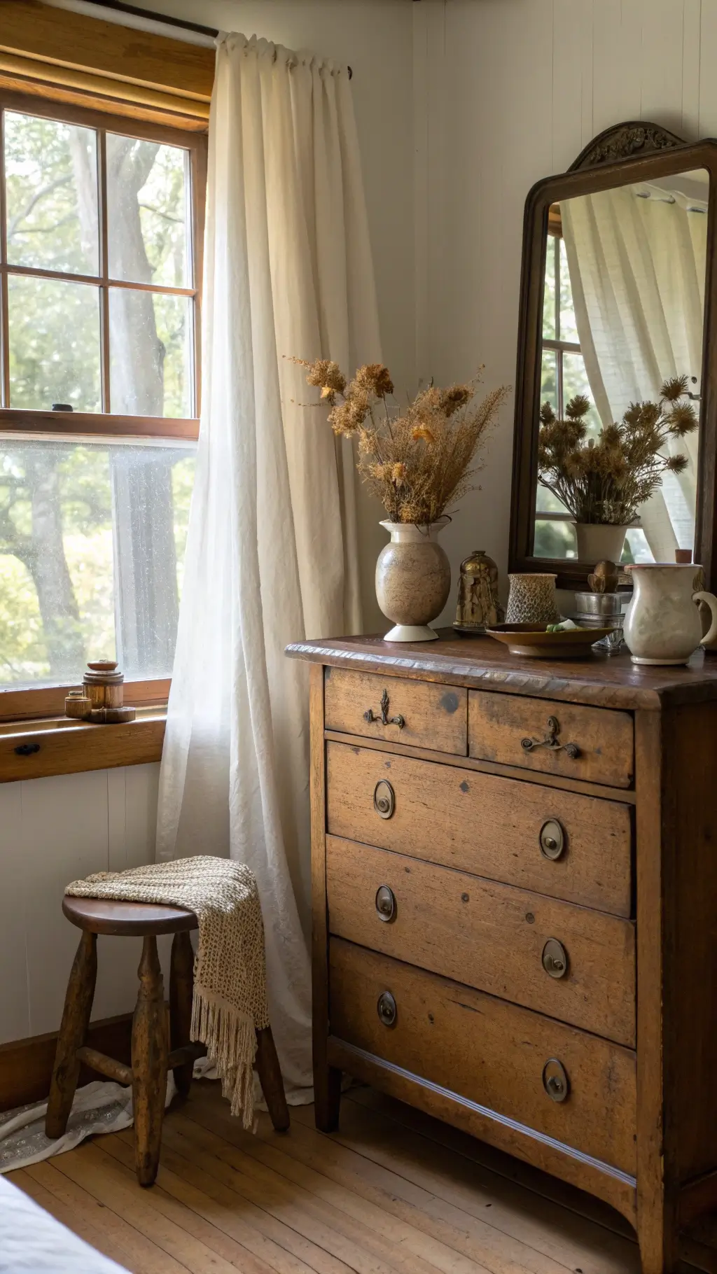Wabi Sabi Bedroom: Creating a Sanctuary of Imperfect Beauty 10 Early morning light illuminating an intimate 12x14ft bedroom vanity with antiquated wooden dresser, handmade ceramic vessels with dried flowers, vintage mirror reflecting soft light, pure linen curtains, and worn wooden stool, captured from a slightly overhead angle.